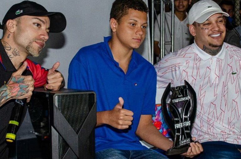 Os influencers @lazarosonicff (esq.) e @dantes.ff (dir.) posam ao lado de participante do evento. (Imagem: Divulgação)